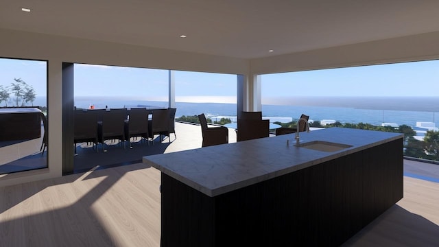 interior space featuring a water view, sink, hardwood / wood-style floors, and a kitchen island with sink