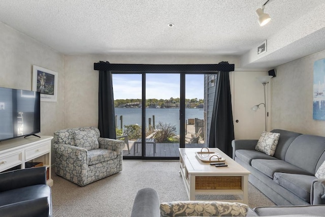 carpeted living room with a water view and a textured ceiling