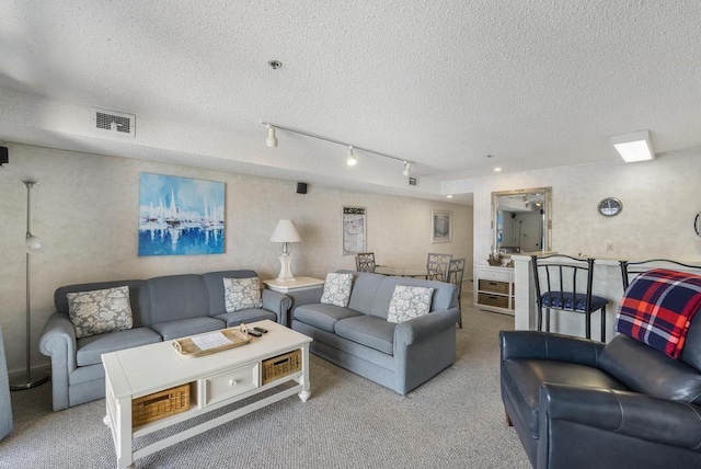 living room featuring rail lighting, light colored carpet, and a textured ceiling