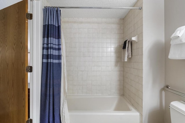 bathroom featuring toilet, shower / bath combo with shower curtain, and a textured ceiling