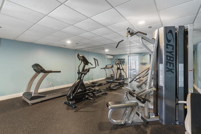 gym with a paneled ceiling and a wall unit AC