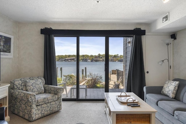 carpeted living room featuring a wealth of natural light, a water view, and a textured ceiling