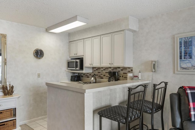 kitchen with white cabinets, kitchen peninsula, a breakfast bar area, and a textured ceiling