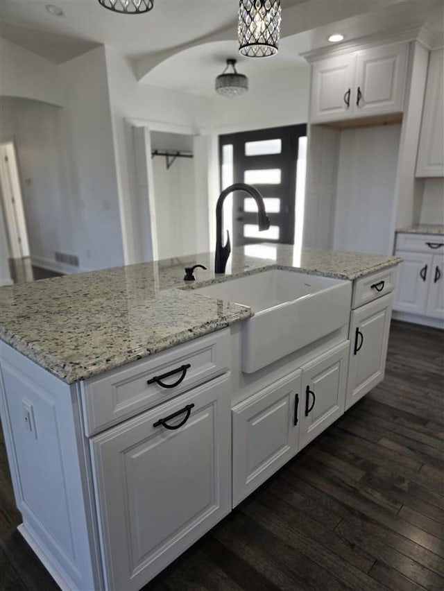 kitchen featuring white cabinetry, sink, hanging light fixtures, dark hardwood / wood-style floors, and an island with sink