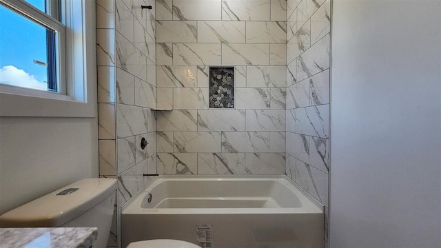 bathroom featuring tiled shower / bath combo and toilet