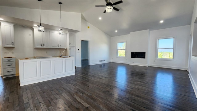 unfurnished living room with high vaulted ceiling, ceiling fan, and dark wood-type flooring