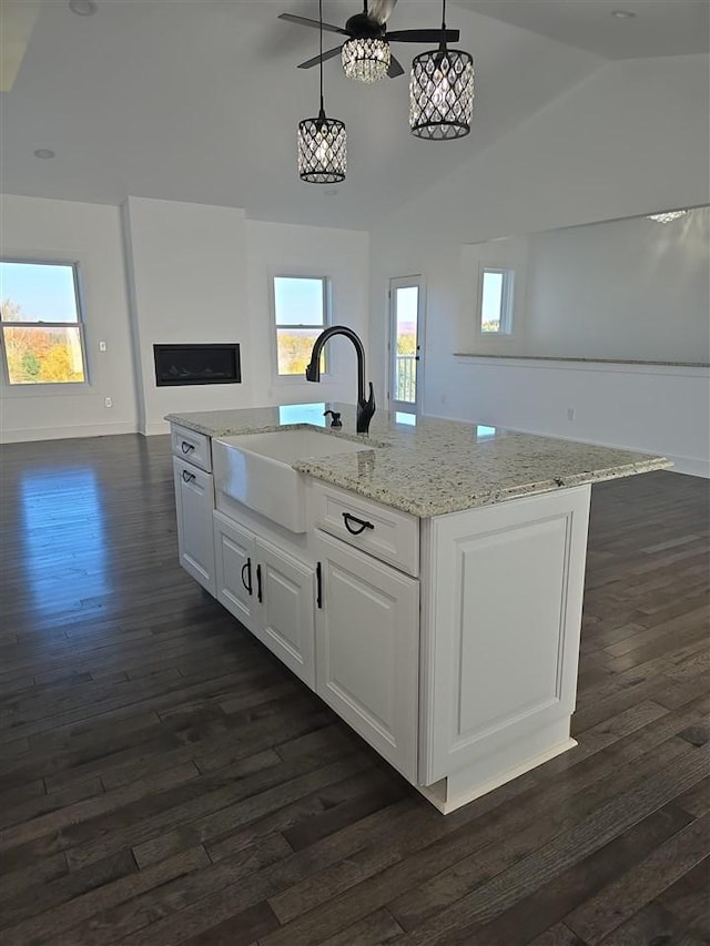 kitchen with pendant lighting, plenty of natural light, white cabinets, and an island with sink