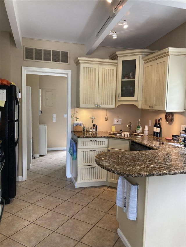 kitchen featuring beamed ceiling, black refrigerator, kitchen peninsula, and cream cabinetry