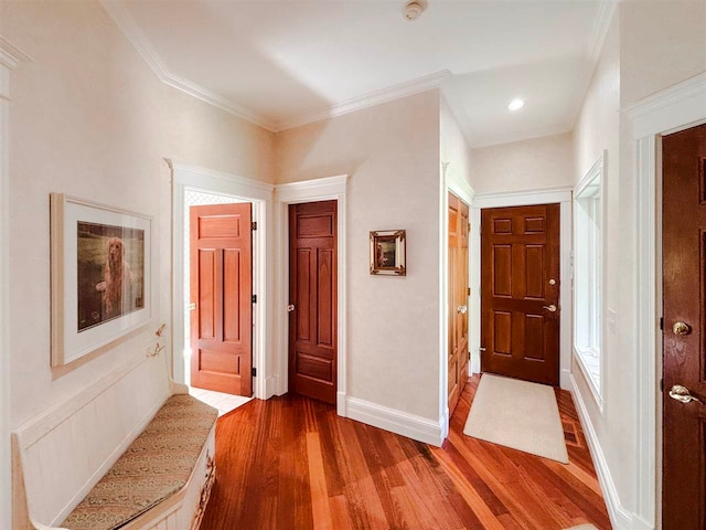 foyer featuring crown molding, baseboards, and wood finished floors