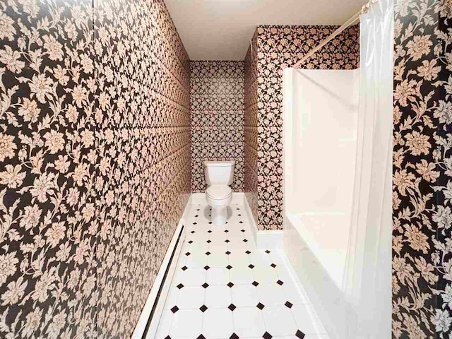 bathroom featuring a baseboard heating unit, tile floors, toilet, and shower / bath combo with shower curtain