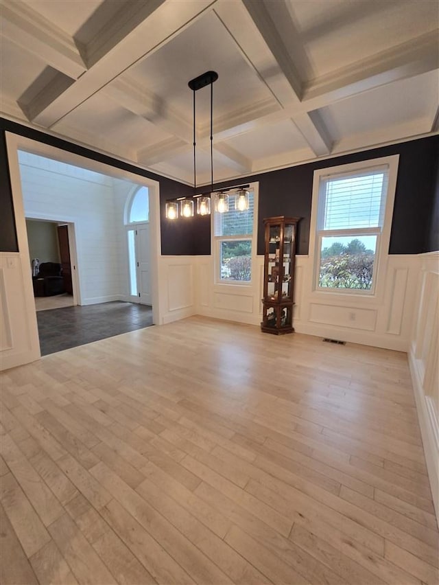 unfurnished dining area with coffered ceiling, light hardwood / wood-style flooring, and a healthy amount of sunlight