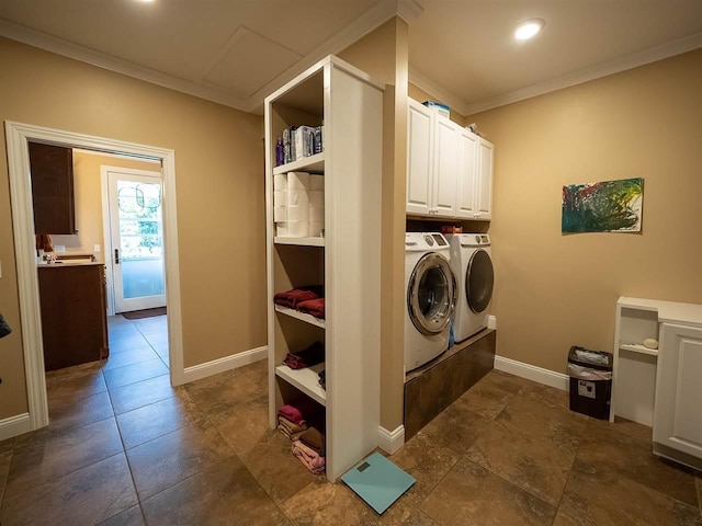 clothes washing area featuring crown molding, washer and clothes dryer, and cabinets