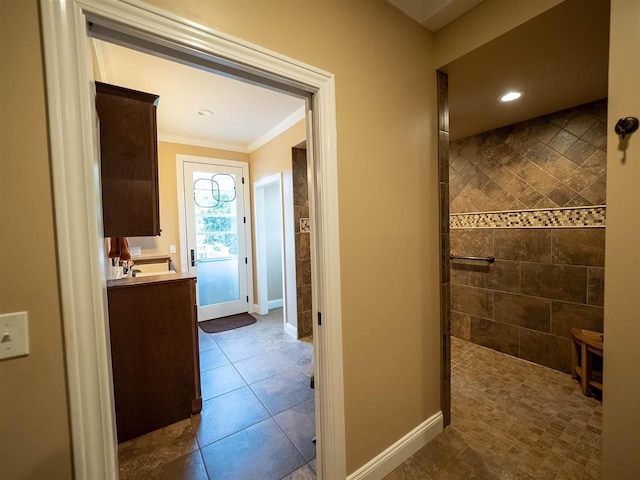 bathroom featuring vanity, tile patterned flooring, ornamental molding, and a tile shower