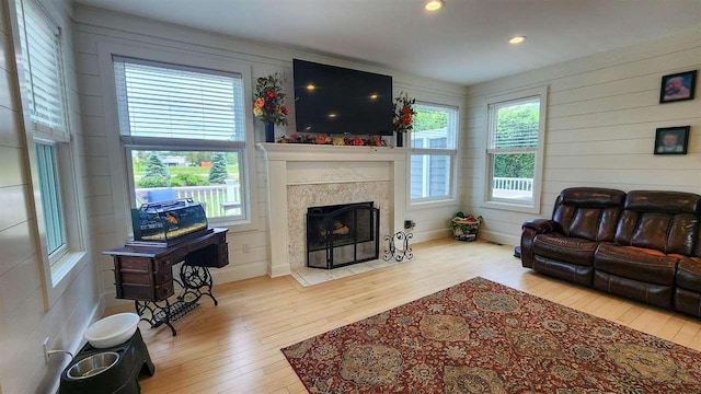 living room with a premium fireplace, a wealth of natural light, and light hardwood / wood-style flooring