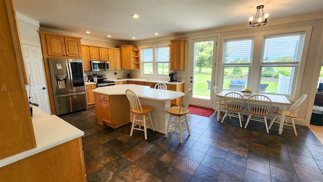 kitchen with an inviting chandelier, a center island, appliances with stainless steel finishes, a kitchen breakfast bar, and pendant lighting