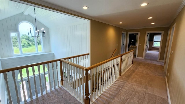 hall featuring crown molding, carpet, a wealth of natural light, and a notable chandelier