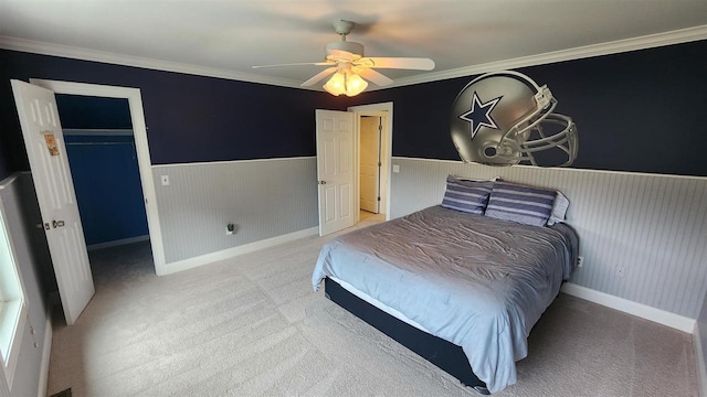 carpeted bedroom featuring a spacious closet, ornamental molding, a closet, and ceiling fan