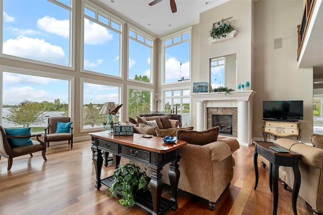 living room featuring wood-type flooring, a high ceiling, ceiling fan, and crown molding