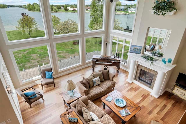 living room featuring a high ceiling, light wood-type flooring, and a water view