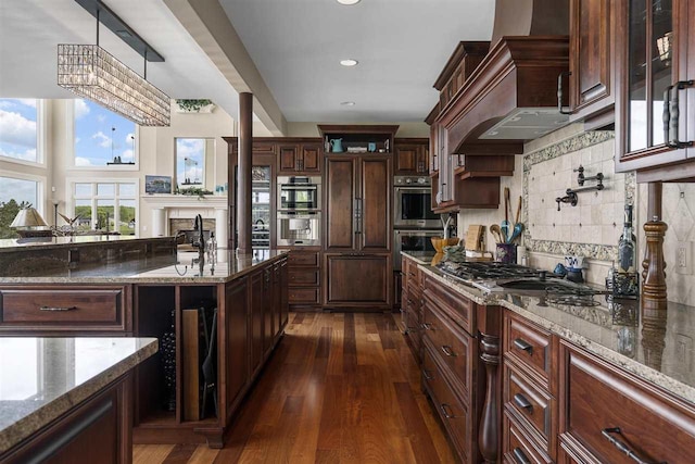 1439 Lindburgh Ln, Cheboygan, MI 49721 - kitchen with custom exhaust hood, dark stone countertops, decorative backsplash, dark wood finished floors, and stainless steel appliances