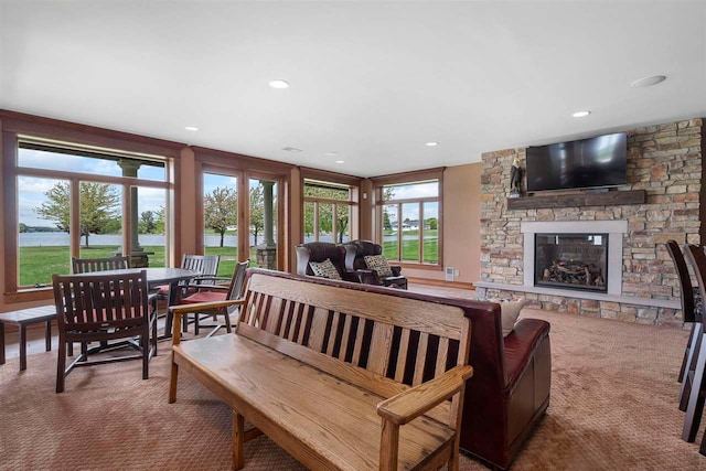 carpeted living room with a fireplace and a water view