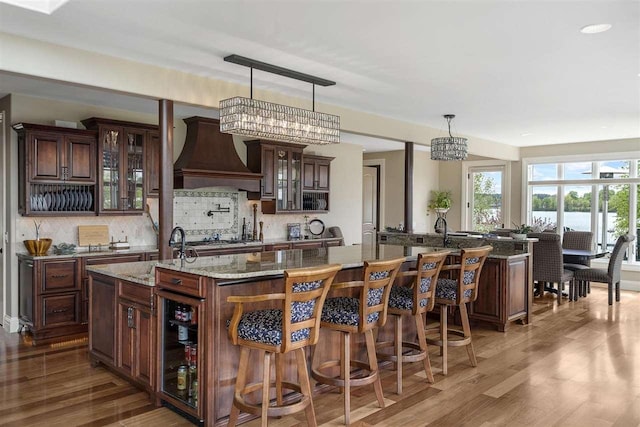 1439 Lindburgh Ln, Cheboygan, MI 49721 - kitchen featuring custom range hood, a spacious island, wood finished floors, and decorative backsplash