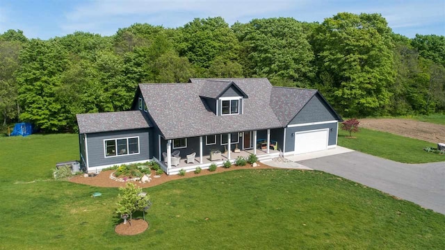 new england style home with a front lawn, covered porch, and a garage