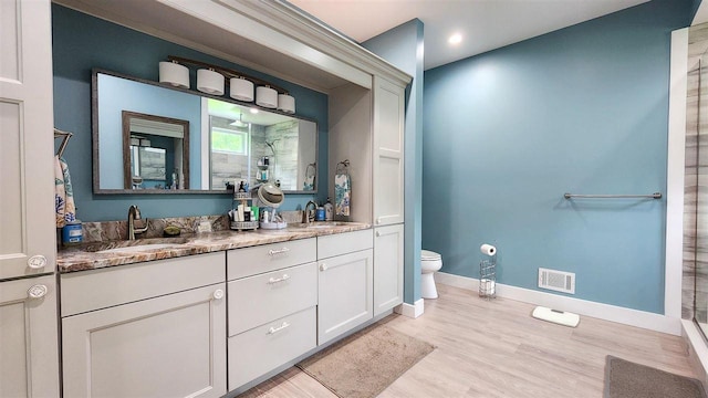 bathroom with hardwood / wood-style flooring, toilet, walk in shower, and vanity