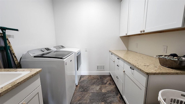 washroom with washer and dryer, cabinets, and sink