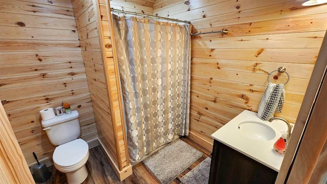 bathroom featuring toilet, vanity, wooden walls, and a shower with shower curtain