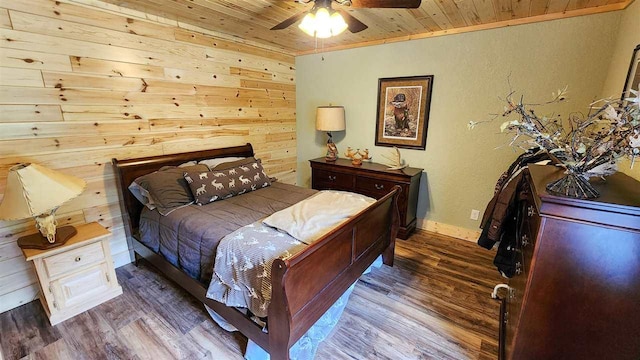 bedroom featuring wood ceiling, wood-type flooring, wood walls, ornamental molding, and ceiling fan