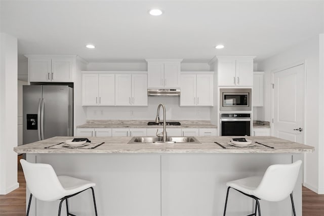 kitchen with a center island with sink, appliances with stainless steel finishes, and dark hardwood / wood-style flooring