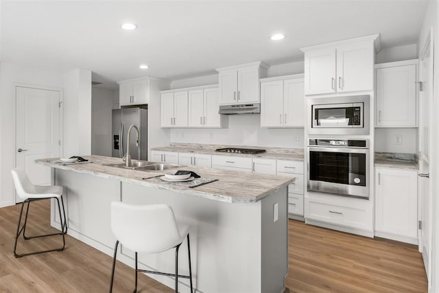 kitchen featuring an island with sink, white cabinetry, light hardwood / wood-style flooring, and stainless steel appliances