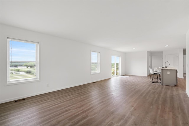 unfurnished living room with sink and hardwood / wood-style flooring