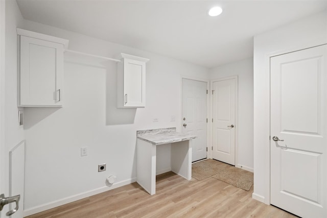 laundry area featuring electric dryer hookup, cabinets, and light wood-type flooring