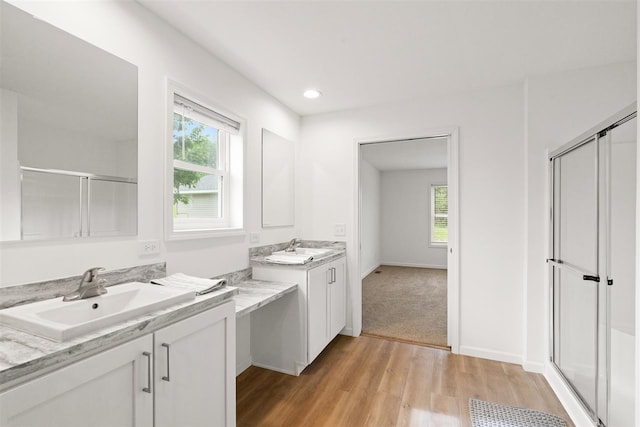 bathroom with an enclosed shower, hardwood / wood-style flooring, double sink, and vanity with extensive cabinet space