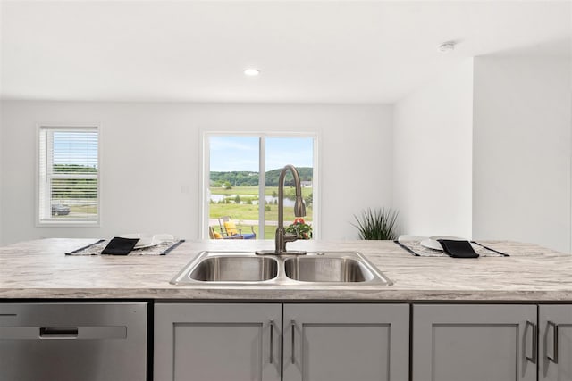 kitchen featuring light stone counters, gray cabinetry, sink, and stainless steel dishwasher