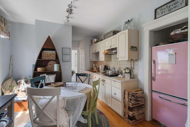 kitchen featuring decorative backsplash, stainless steel fridge, gas stovetop, light hardwood / wood-style flooring, and cream cabinetry