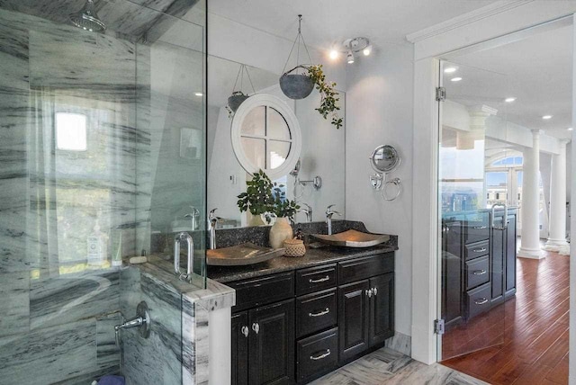 bathroom with hardwood / wood-style floors, vanity, ornate columns, and a shower with door