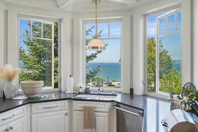 interior space featuring decorative light fixtures, a water view, white cabinetry, and sink