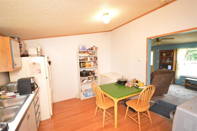 dining area featuring a textured ceiling, ceiling fan, crown molding, sink, and light hardwood / wood-style flooring