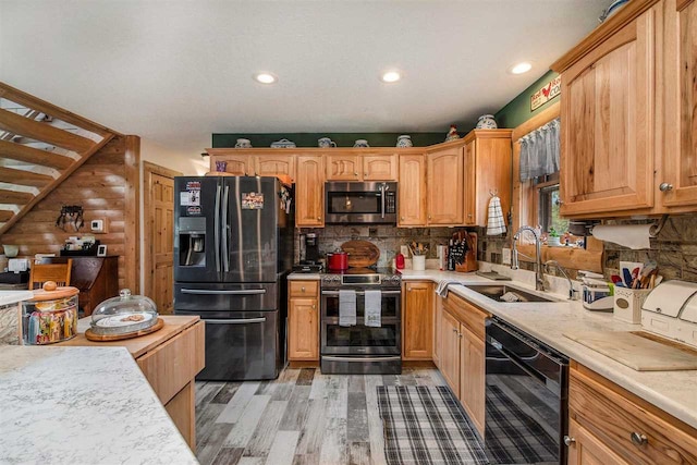 kitchen featuring decorative backsplash, light hardwood / wood-style floors, black appliances, and sink