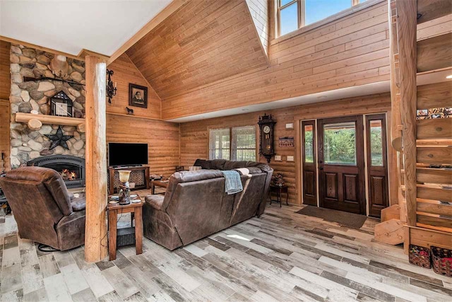 living room featuring a stone fireplace, light wood-type flooring, high vaulted ceiling, and wooden ceiling