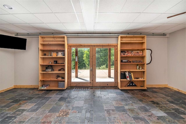 basement featuring french doors, dark tile patterned floors, and a barn door