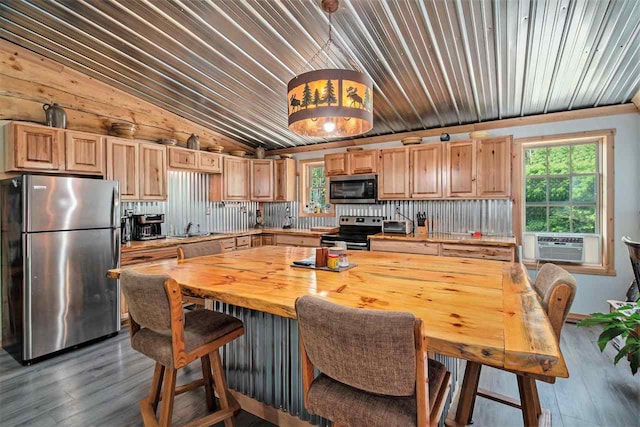 kitchen featuring cooling unit, appliances with stainless steel finishes, wood-type flooring, and backsplash