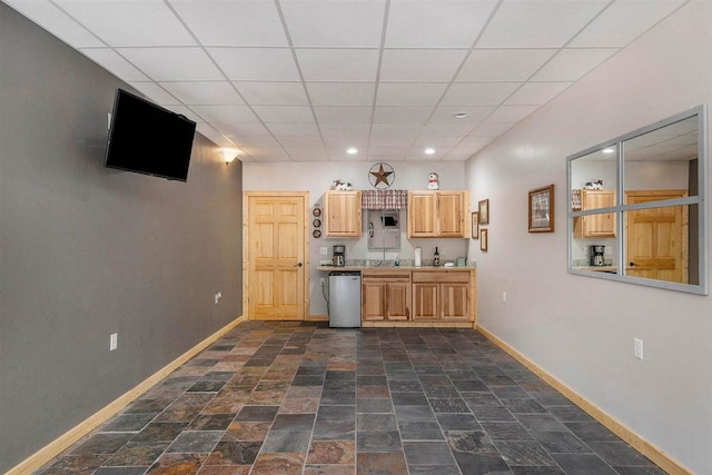 kitchen featuring dark tile patterned floors, dishwasher, light brown cabinetry, a paneled ceiling, and sink