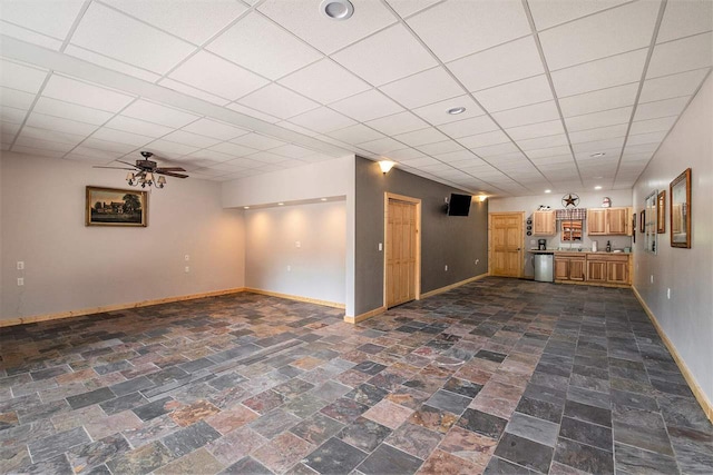 basement featuring a paneled ceiling, ceiling fan, and dark tile patterned flooring