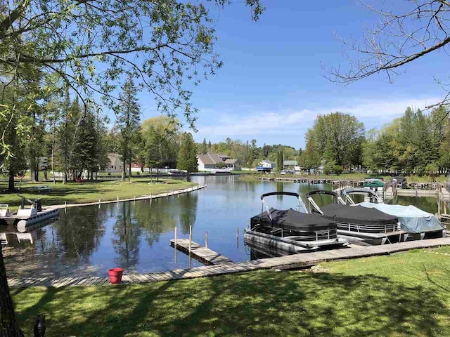 view of dock featuring a lawn and a water view