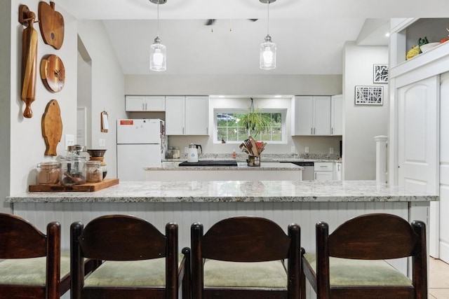 kitchen featuring light stone countertops, white cabinetry, white fridge, and decorative light fixtures