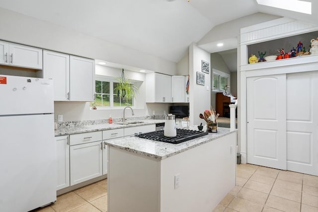 kitchen with lofted ceiling with skylight, white cabinetry, sink, white refrigerator, and a center island